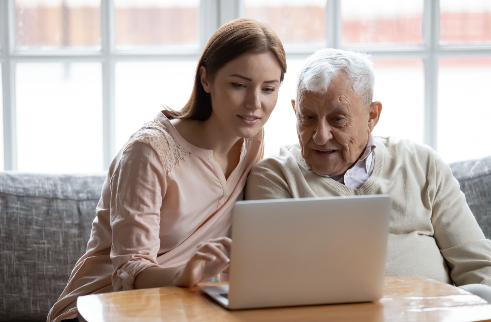 A senior and their adult grandchild use a laptop to browse local options for assisted living.