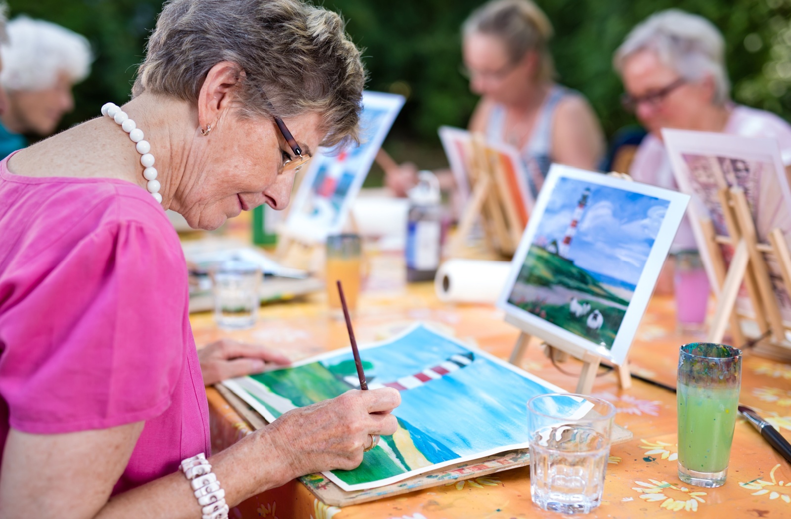 A group of happy older adults in senior living performing out therapy outside.
